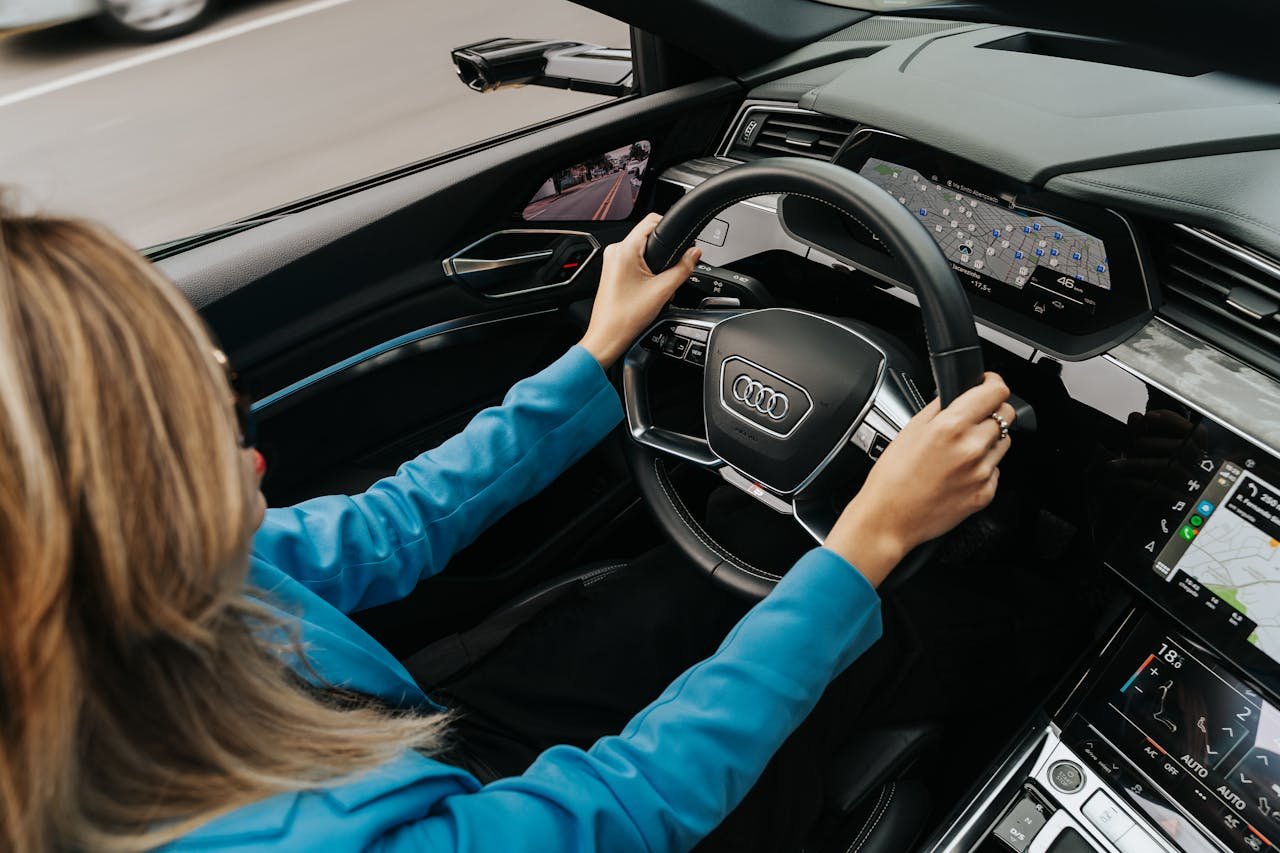 mobile-02 High angle view of a woman driving a modern Audi car, showcasing the dashboard and steering wheel.