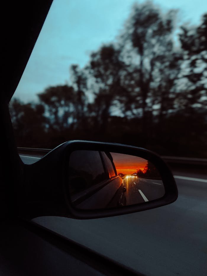 pexels photo 20691271 View of a stunning sunset reflecting in a car's side mirror while driving on a road.