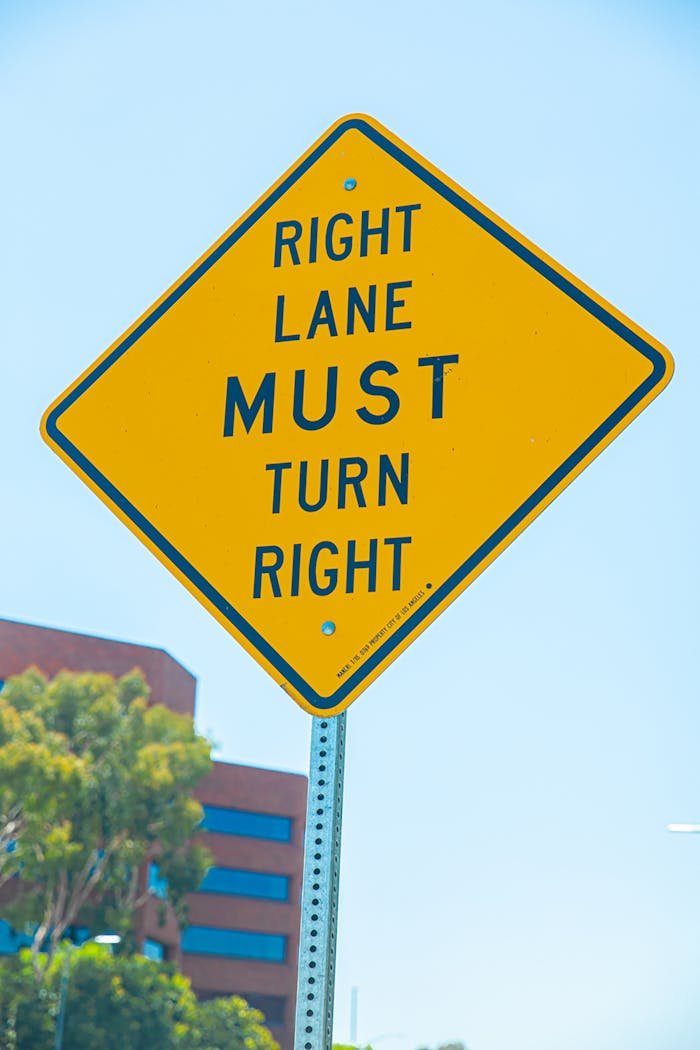 creative-01 Yellow diamond traffic sign indicating right lane must turn right in urban setting.